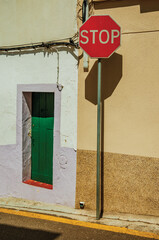 STOP road sign in front colorful house with wooden door on sunny day in Campo Maior. A little town with Moorish and medieval influences in Portugal.