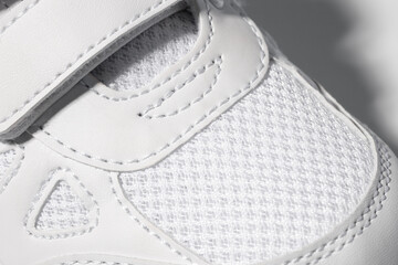 Macro photography of the toe of white sneakers. Children's sports sneakers made of leather, sewn...