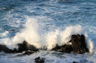 sea landscape, blue sea waves crashing against the rocks, big splash in the ocean, white sea foam, sun