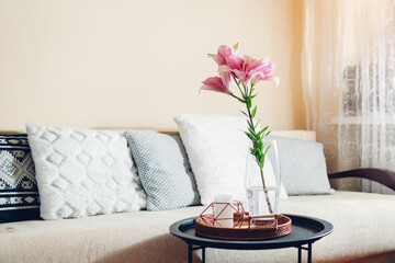 Interior and home decor. Fresh pink lily flowers put in vase in living room. Bouquet of blooms on coffee table