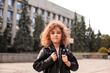 The little girl is walking around the city with a bag