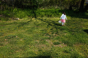 Easter egg hunt little girl outside in park