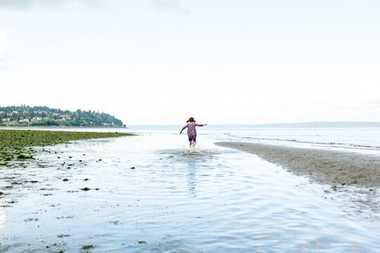 Wide angle view of a child running through shallow water by the beach