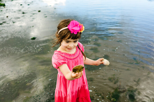 High angle view of a young girl looking at a sea shell on the beach