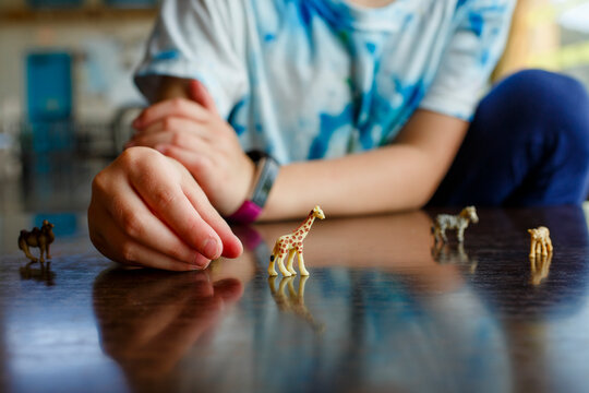 close-up of little girl playing with miniature toy animals on tabletop