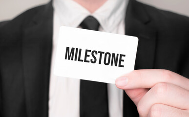 Businessman holding a card with text Milestone
