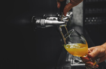 bartender hand at beer tap pouring a draught beer in glass serving in a restaurant or pub