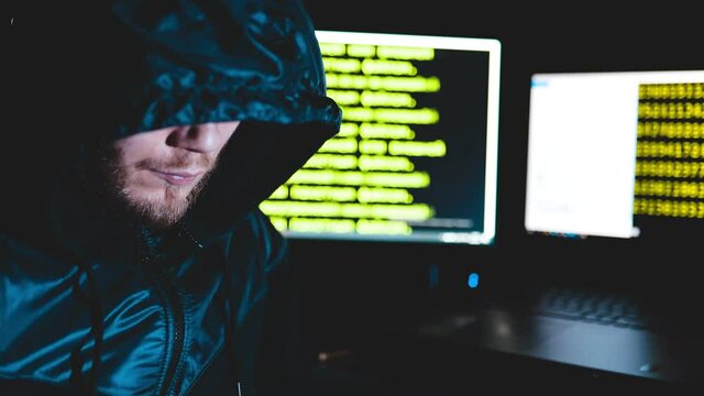 male hacker criminal in the hood at the computer coding, cybercrime concept