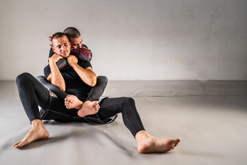 Brazilian jiu jistu bjj no-gi grappling training two male athletes drilling technique back control...