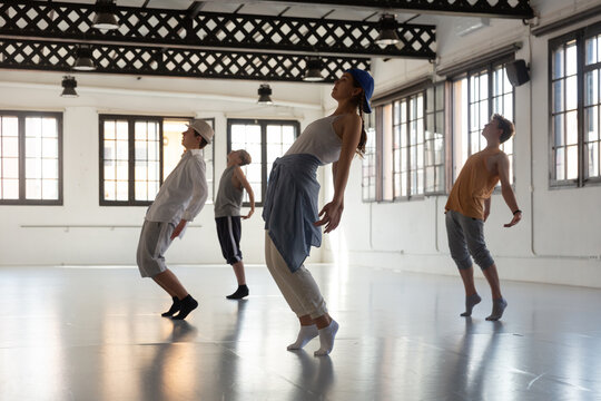 Teenager girl and boys exercising hip-hop dancing indoors