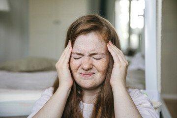 A young woman suffers from a headache, migraine. Consequences of covid