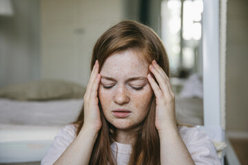 A young woman suffers from a headache, migraine. Consequences of covid