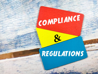 Business concept. Text COMPLIANCE AND REGULATIONS on color wooden board on a wooden background.