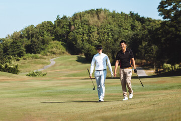 Golfers happily walking with golf clubs on green grass in the morning.