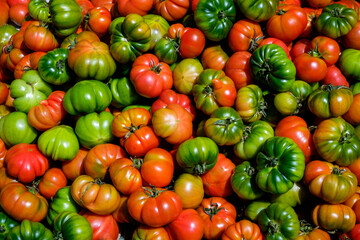 A pile of red and green heirloom tomatoes in a market in Martina Franca in the Puglia region of...