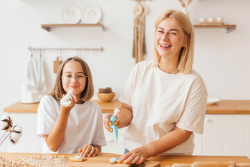 Obraz na płótnie Canvas Mother and little daughter bake cookies and have fun in the kitchen. Homemade food. Happy loving family are preparing cookies together. Happy childhood