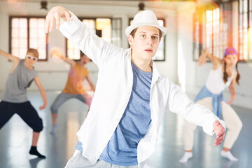 Emotional teenage male dancer having hip-hop group training at dance hall