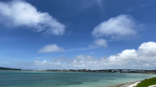 OKINAWA, JAPAN - JUNE 2021 : View of Senaga island and beach (Ocean or sea). Clear blue summer sky and clouds. Wide view time lapse shot in daytime.