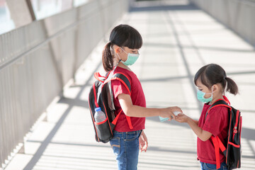 Little girl and sister wearing face mask going to school during coronavirus outbreak. Safety mask for illness prevention. Mom and kid at school during covid 19 pandemics.