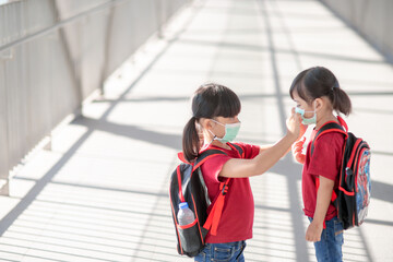 Little girl and sister wearing face mask going to school during coronavirus outbreak. Safety mask for illness prevention. Mom and kid at school during covid 19 pandemics.