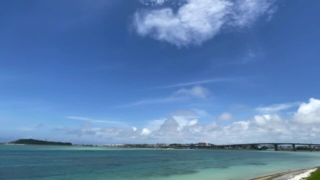 OKINAWA, JAPAN - JUNE 2021 : View of Senaga island and beach (Ocean or sea). Clear blue summer sky and clouds. Wide view time lapse shot in daytime.