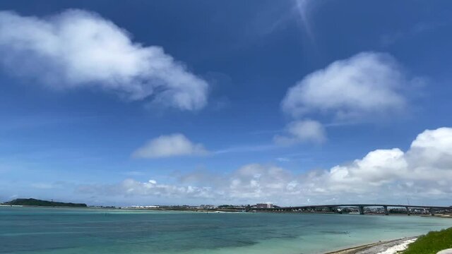 OKINAWA, JAPAN - JUNE 2021 : View of Senaga island and beach (Ocean or sea). Clear blue summer sky and clouds. Wide view time lapse shot in daytime.