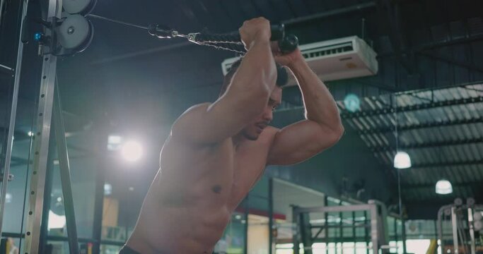 Muscular man working out exercise for triceps push down weightlifting with pull cable cross machine to flexing muscles at fitness gym, Sport fit workout bodybuilding concept