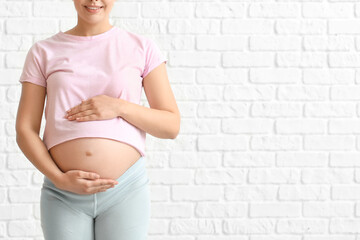 Young pregnant woman on brick background