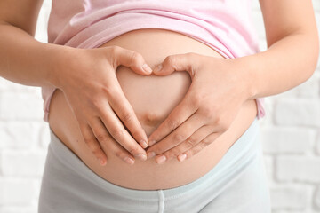 Young pregnant woman on brick background, closeup