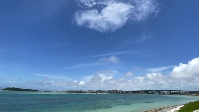 OKINAWA, JAPAN - JUNE 2021 : View of Senaga island and beach (Ocean or sea). Clear blue summer sky and clouds. Wide view time lapse shot in daytime.