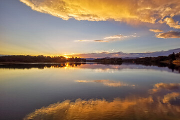 The last moment before sunset with a perfectly clear evening light over a calm coastal estuary in eastern Australia, making a perfect reflection of the overhead clouds glowing with the sunset light.