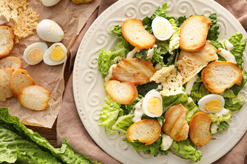 Plate with tasty Caesar salad on table, closeup