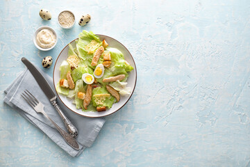 Plate with tasty Caesar salad and sauce on color background