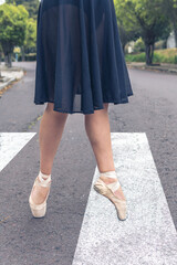 closeup of legs in pointe ballet shoes with black skirt on a pedestrian crossing
