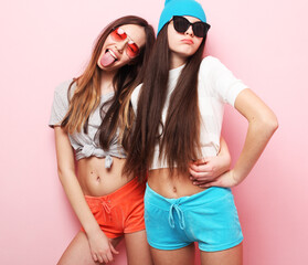 happy smiling pretty teenage female friends hugging over pink background