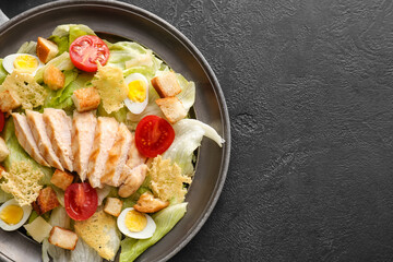 Plate with tasty Caesar salad on dark background