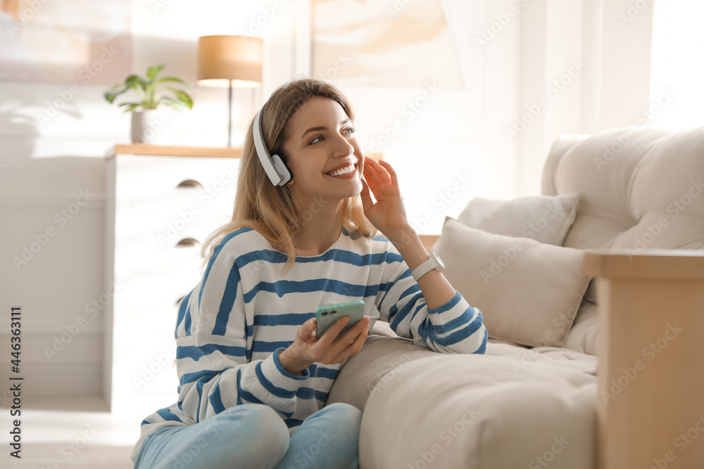 Wall mural Young woman listening to music at home