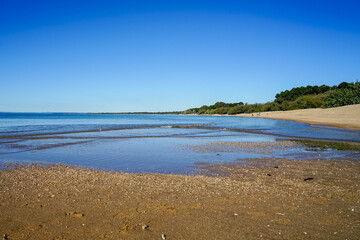 Gentle waves lap the sandy shore at low tide, at Hervey Bay, Queensland on a sunny afternoon 