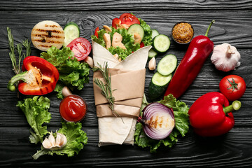 Composition with tasty doner kebab, vegetables and sauces on dark wooden background