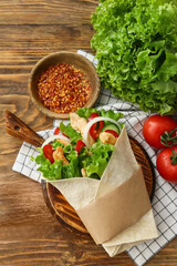 Board with tasty doner kebab and spices on wooden background