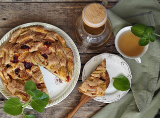 Autumn homemade charlotte fruit pie on a wooden ancient natural table with tea, teapot and mint.Place for text.