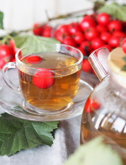 The hawthorn harvesting season for future use. Alternative medicine. Benefits of herbal tea with hawthorn.Cup on a white plate with berries.