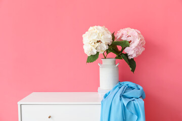 Vase with beautiful hydrangea flowers on shelf near color wall