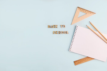 School supplies: an empty notebook, wooden pencils and rulers. The inscription Back to school is made of wooden letters. Zero waste, accessories made of eco-friendly materials. 