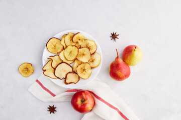 Dried sliced apple and pear in a plate on a light gray background. Homemade fruit chips. Vegan dessert sugar free.