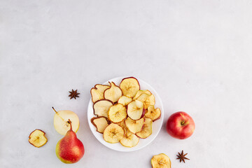 Apple and pear chips on a plate on grey background. Homemade fruit dried sliced. Vegan dessert sugar free. Top view. Copy space.