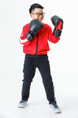 Lovely cutout portrait of young healthy Asian boy wearing red jacket, black pants, and boxer gloves standing tight and ready to fight strongly with happily smiling as enjoy boxing practice