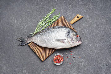 Board with raw dorado fish on dark background