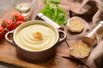 Pot of tasty mashed potatoes with garlic and vegetables on wooden background