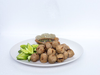 Grilled meatballs, skewers, meatballs, beef noodles with vegetables and dipping sauces burnt on a plate, and white Asian food.